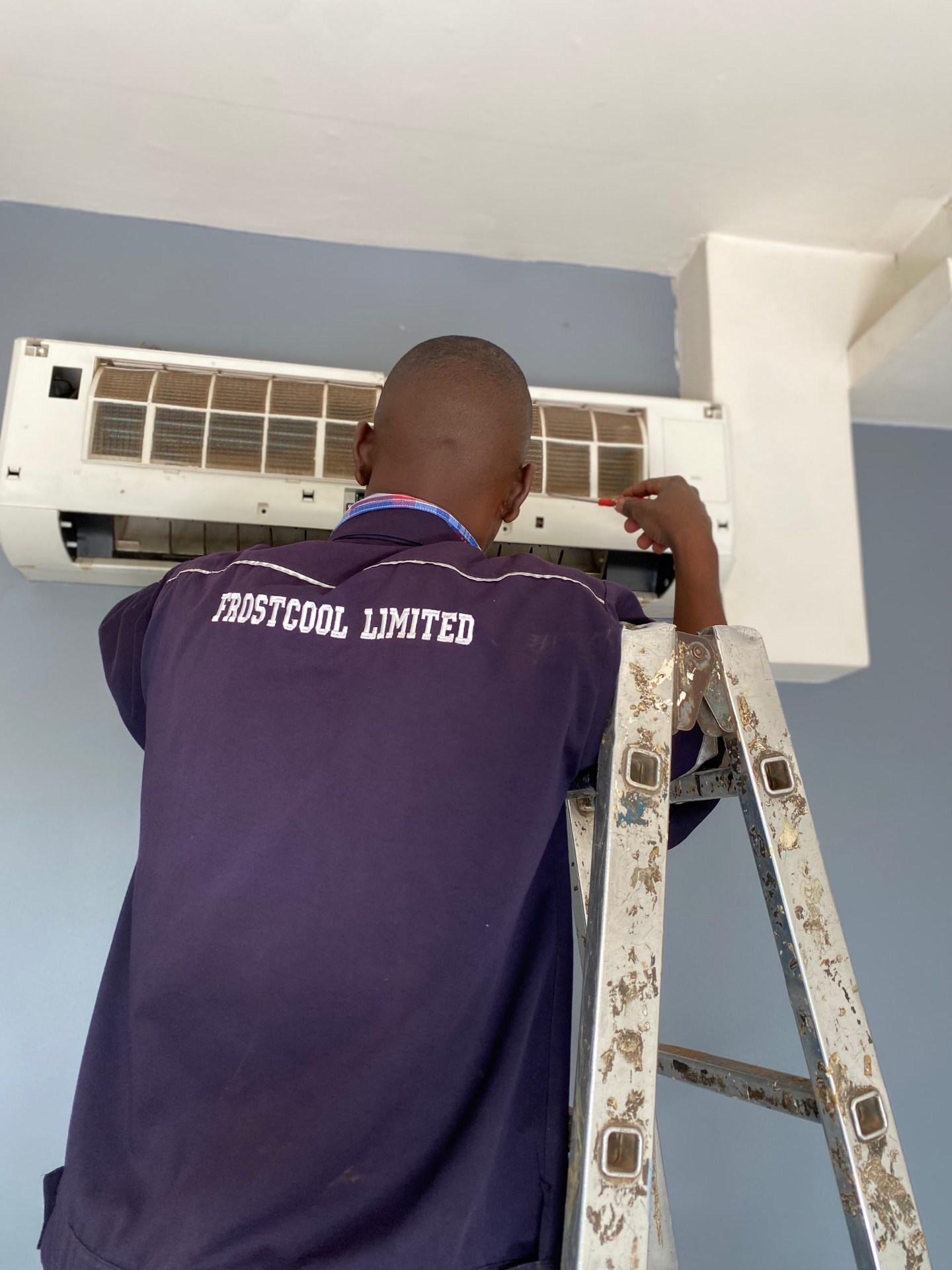 FrostCool Limited technician cleaning an indoor AC unit